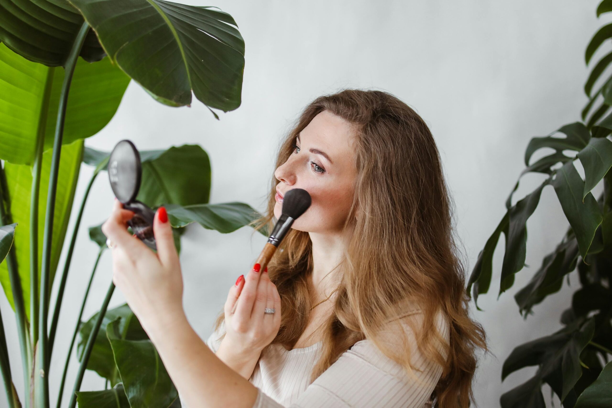Close-up shot of hands applying blush onto cheeks using a fluffy brush