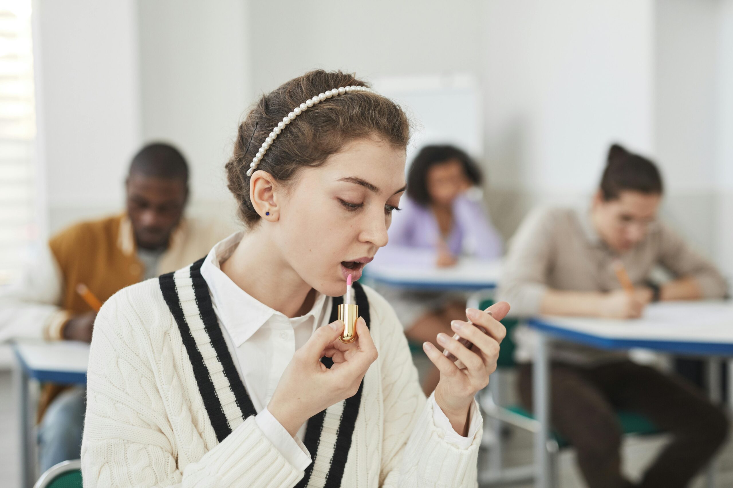 A photo of a student applying makeup with drugstore products in a dorm room