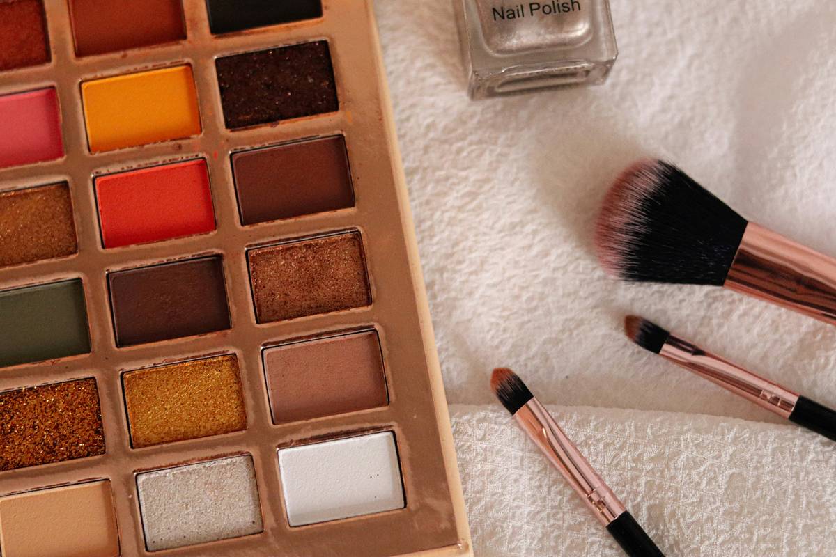 A collection of vibrant drugstore makeup products neatly arranged on a white surface