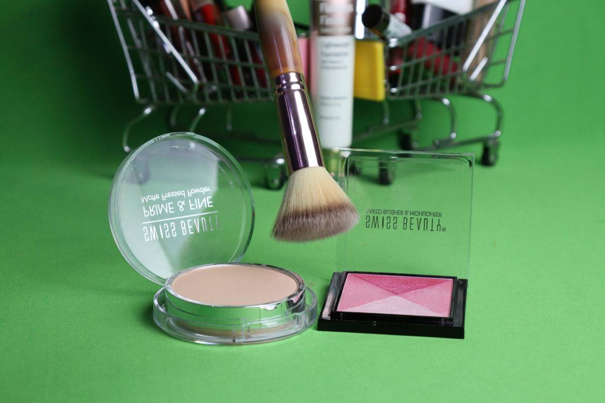 A hand holding a pot of creamy blush being applied to cheeks and lips