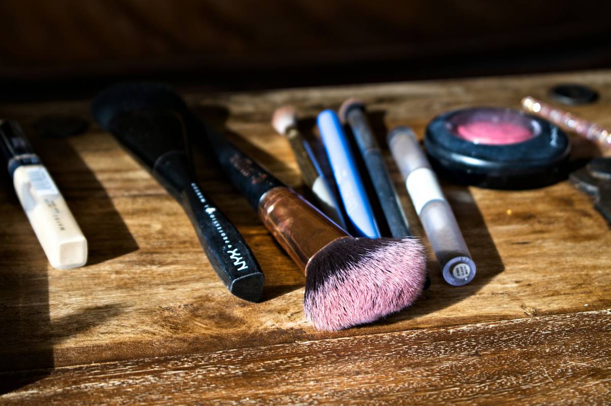 Drugstore makeup displayed neatly on a white table including lipsticks, eyeshadows, and mascaras